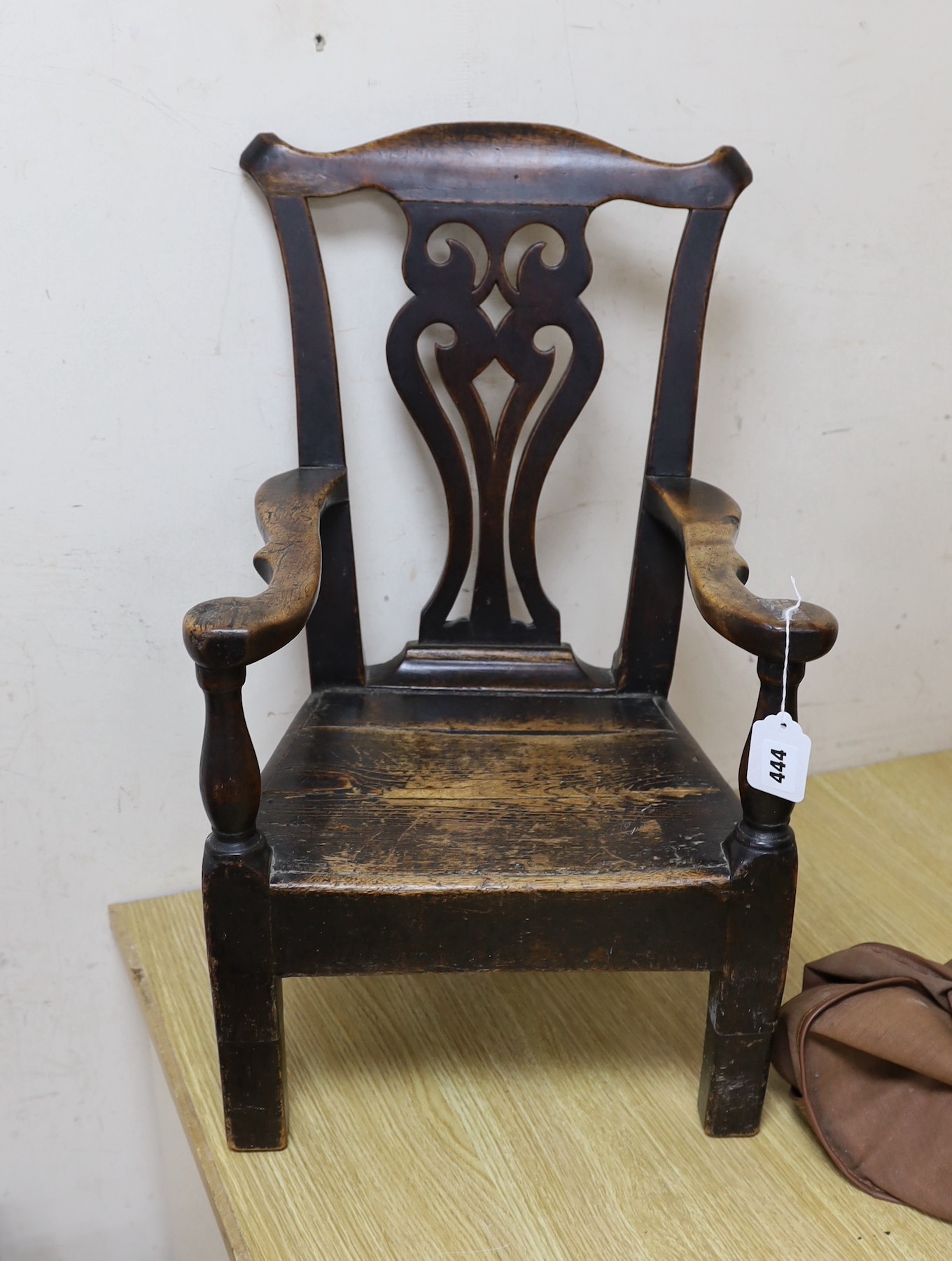 An 18th century pine and fruitwood child's elbow chair, 61cms high (feet spliced)